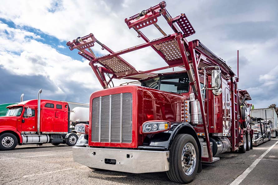 An empty red auto transport semi truck in a parking lot.