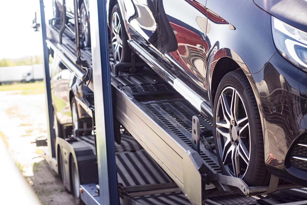 Cars securely loaded on an open auto transport trailer.
